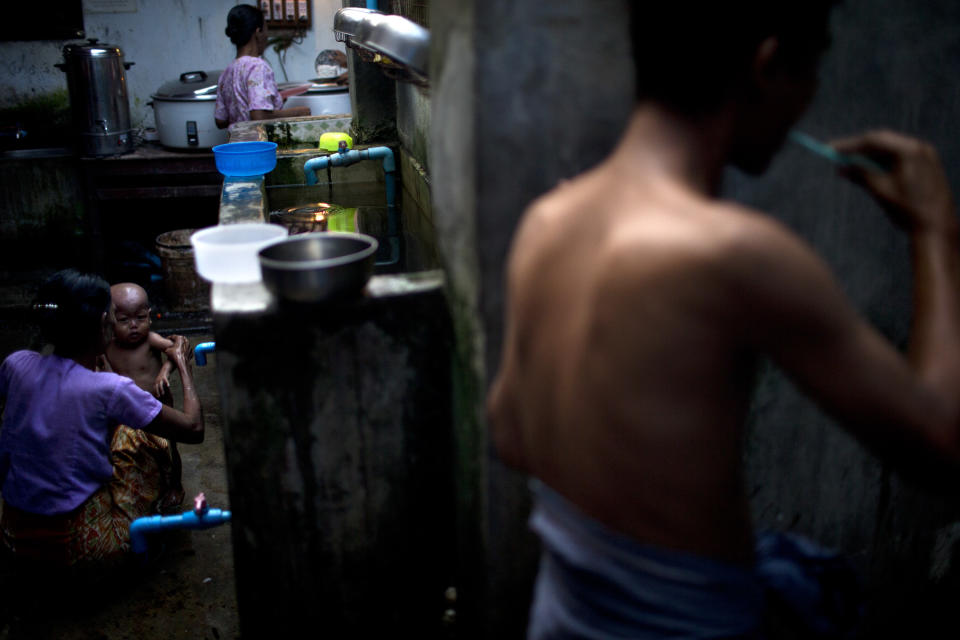 In this Aug. 29, 2012 photo, an HIV-infected patient, front, brushes his teeth while an HIV-infected mother gives her baby a bath and another patient, back, prepares rice for dinner at an HIV/AIDS center on the outskirts of Yangon, Myanmar. Following a half century of military rule, care for HIV/AIDS patients in Myanmar lags behind other countries. Half of the estimated 240,000 people living with the disease are going without treatment and 18,000 are dying from it every year. (AP Photo/Alexander F. Yuan)