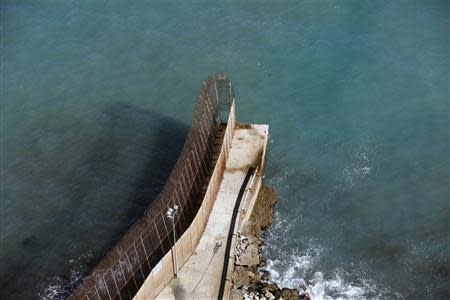 The border fence which separates Morocco and Spain's north African enclave Melilla runs all the way to the sea at the farthest western point of the 12.5-square-kilometre territory's border December 3, 2013. REUTERS/Juan Medina