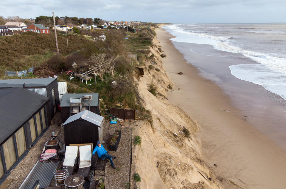 <p>Former soldier Lance Martin, 63, sits in the back garden of his home in Hemsby, Norfolk, where his back door is now no more than six metres (20ft) from the cliff edge after more land has been lost to the sea in the past few days. Around 30 metres of cliff were lost to the tides when the Beast from the East battered the coast in March 2018, and Mr Martin's home is the last remaining from a row of 13 houses. Picture date: Wednesday April 7, 2021.</p>
