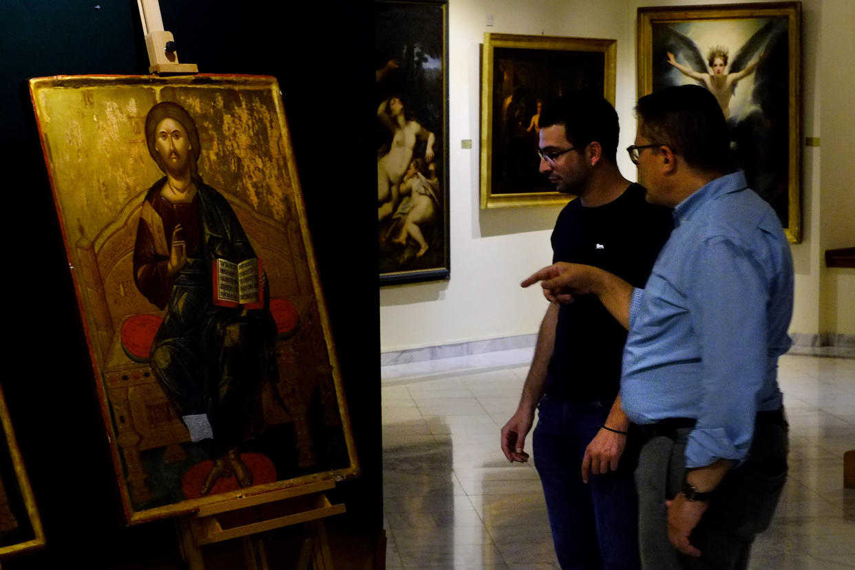 Director of Byzantine museum in Cyprus Ioannis Eliades, right, stands and talks in front of a looted 500 year-old Orthodox icon of the Enthroned Christ is seen at the Byzantine Museum after it was returned, in capital Nicosia, Cyprus, on Tuesday, July 12, 2022. A 500 year-old Orthodox icon of the Enthroned Christ that was looted from a 12th century church in the breakaway north of ethnically divided Cyprus was repatriated after the end of a years-long legal journey from Zurich. (AP Photo/Petros Karadjias)