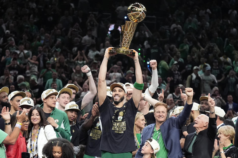 Boston Celtics forward Jayson Tatum holds, center, up the Larry O'Brien Championship Trophy as he celebrates with the team after they won the NBA basketball championship with a Game 5 victory over the Dallas Mavericks, Monday, June 17, 2024, in Boston. (AP Photo/Charles Krupa)