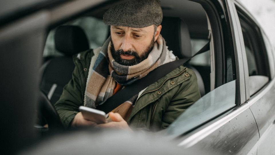 Man driving car and using phone to send text message.