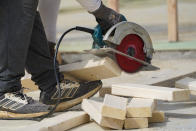 FILE - In this March 16, 2021 file photo, a workman cuts sections of a bean at a housing site in Madison County, Miss. Rising costs and shortages of building materials and labor are rippling across the homebuilding industry, which accounted for nearly 12% of all U.S. home sales in July. As building a new home gets more expensive, some of those costs are passed along to buyers. (AP Photo/Rogelio V. Solis, File)