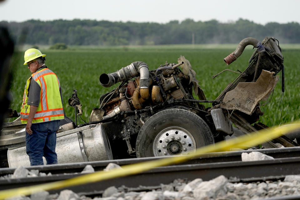 A worker looks over a dump truck that collided with an Amtrak train, causing it to derail Monday, June 27, 2022, near Mendon, Mo. (AP Photo/Charlie Riedel)