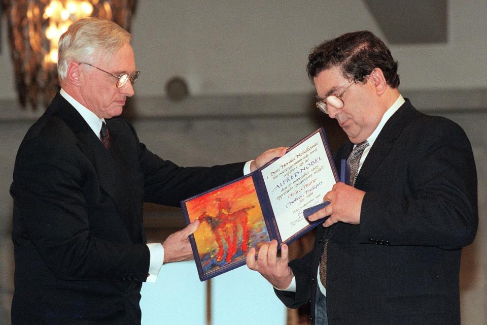 FILE - In this Dec. 10, 1998 file photo, John Hume, right, looks at the Nobel Peace Prize diploma which he received from Francis Sejersted, left, chairman of the Norwegian Nobel Peace Prize Committee during the award ceremony in Oslo Town Hall. The family of politician John Hume, who won Nobel Peace Prize for work to end violence in Northern Ireland, says he has died. He was 83. The Catholic leader of the moderate Social Democratic and Labour Party , Hume was regarded by many as the principal architect behind the peace agreement. (AP Photo/Bjoern Sigurdsoen/NTB/POOL)