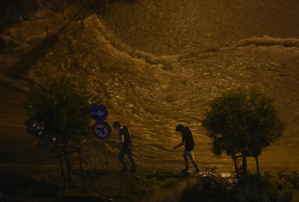 People walk next to floodwaters blocking the road due to the heavy rain in Basaksehir district of Istanbul, Turkey, Tuesday, Sept. 5, 2023. Flash floods triggered by heavy rains swept through a campsite in northwest Turkey on Tuesday, killing at least two people, officials said. Four other people were reported missing. (AP Photo/Khalil Hamra)