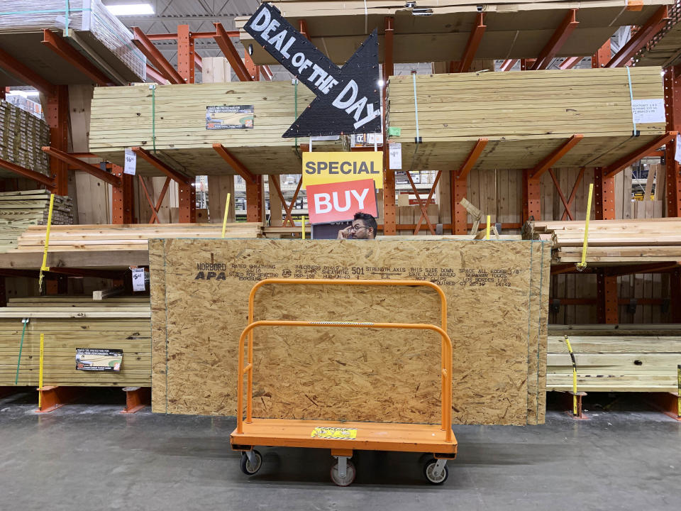 A shopper stands with a dolly of plywood at The Home Depot ahead of Hurricane Dorian on Thursday, Aug. 29, 2019, in Pembroke Pines, Fla. (AP Photo/Brynn Anderson)