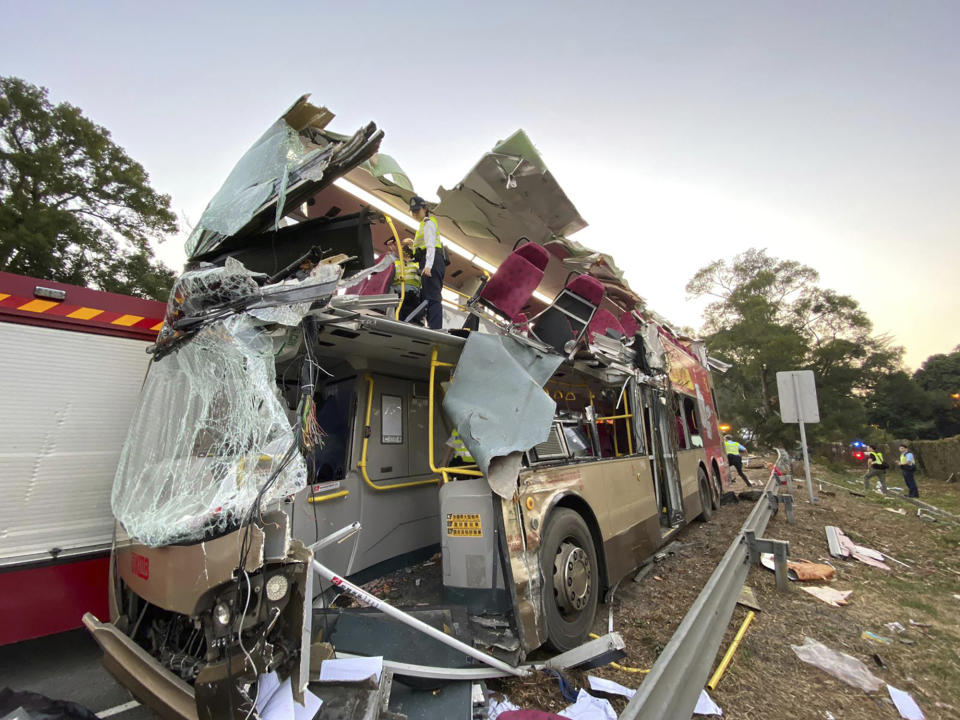 In this photo provided by Hong Kong Police Force, police officers investigate a double-decker bus after its crash on a highway from the town of Fanling, in Hong Kong Wednesday, Dec. 18, 2019. Hong Kong emergency services say a violent crash of a double-decker bus has killed multiple people and injured more than 20 others. (Hong Kong Police Force via AP)