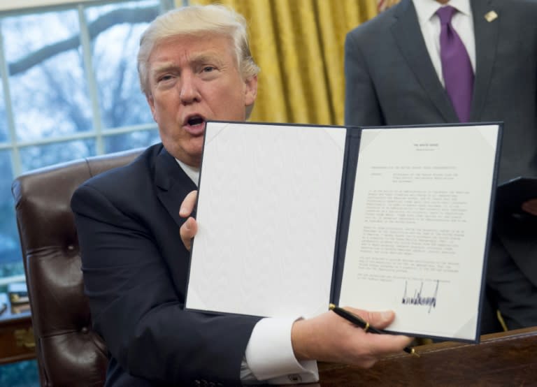 US President Donald Trump holds up an executive order withdrawing the US from the Trans-Pacific Partnership after signing it in the Oval Office of the White House on January 23, 2017