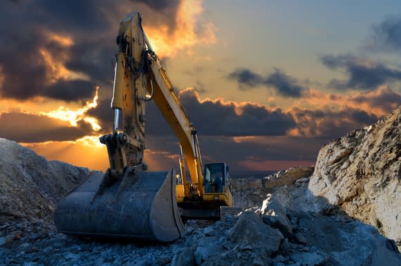 An excavator in a stone quarry at sunset.