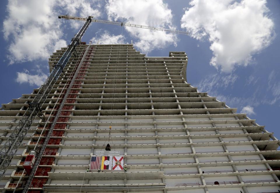 FILE - In this July 9, 2018 file photo, two of the final steel beams with signatures along with the American, Seminole Tribe, and the State flags are hoisted during the "Topping Out" ceremony where the beams of the highly anticipated project were ceremonially set atop the giant framework of the guitar shaped tower in Hollywood, Fla. It looks like the guitar Led Zeppelin's Jimmy Page played. But this one is 450 feet (137 meters) tall and is a light-beam hotel that the Seminole Tribe wants to become South Florida's latest tourist destination. The Guitar Hotel's grand opening is Thursday, Oct. 24, 2019, on the tribe's land in Hollywood. It's the latest step in the Seminole Hard Rock empire, which includes naming rights on the Miami-area stadium where the 2020 Super Bowl will be played. (Carl Juste/Miami Herald via AP, File)