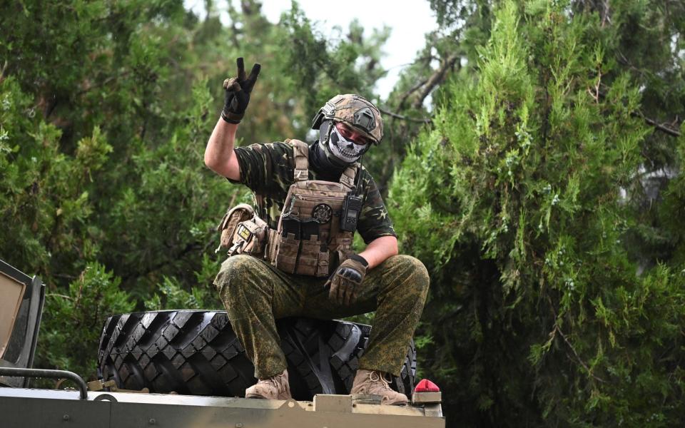 A fighter of Wagner private mercenary group flashes a victory sign in a street near the headquarters of the Southern Military District in the city of Rostov-on-Don