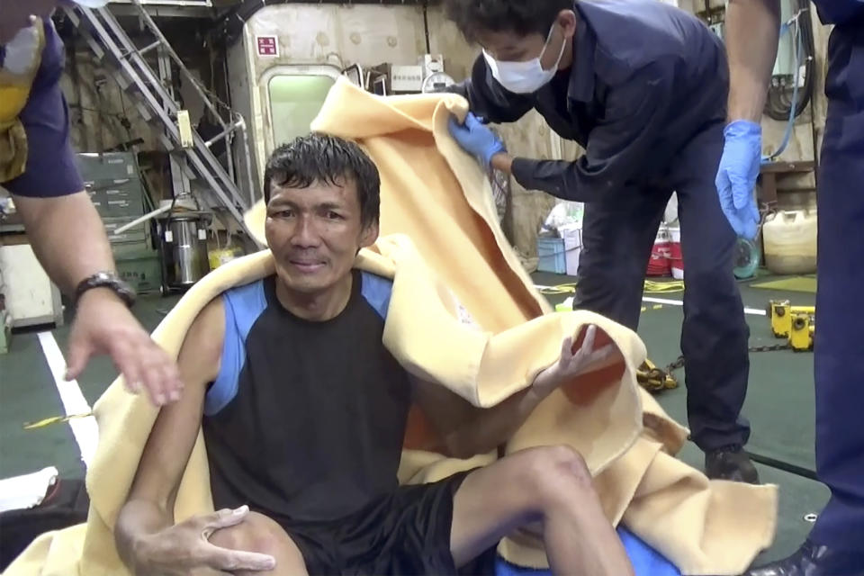 In this image made from video released by the 10th Regional Japan Coast Guard Headquarters, a rescued crew member of a Panamanian cargo ship sits, wrapped in blanket, at Japanese Coast Guard members, off the Amami Oshima, Japan Wednesday, Sept. 2, 2020. Japanese rescuers have safely plucked the crew member from the sea while searching for the cargo ship carrying more than 40 crew and thousands of cows went missing after sending a distress call off the southern Japanese island. (The 10th Regional Japan Coast Guard Headquarters via AP)