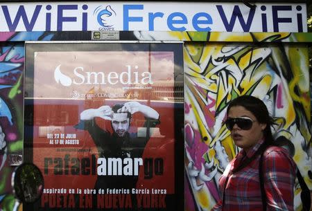 A woman walks past a newspaper kiosk advertising Spanish wireless network provider Gowex in Madrid in this July 7, 2014 file photo. REUTERS/Andrea Comas/Files