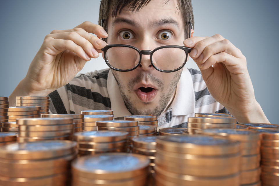 A surprised man looking at stacks of coins.