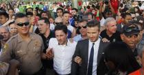 David Beckham (front, in tie) makes his way through a crowd while visiting the Kendall Soccer Park in suburban Miami February 5, 2014. REUTERS/Andrew Innerarity