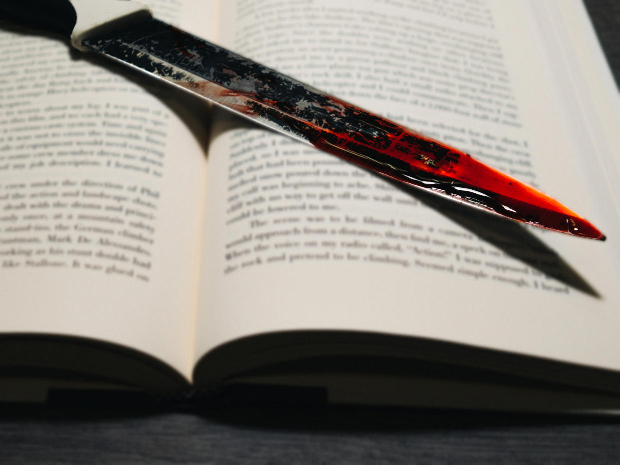  Vignetted image of a bloody kitchen knife on a book . 