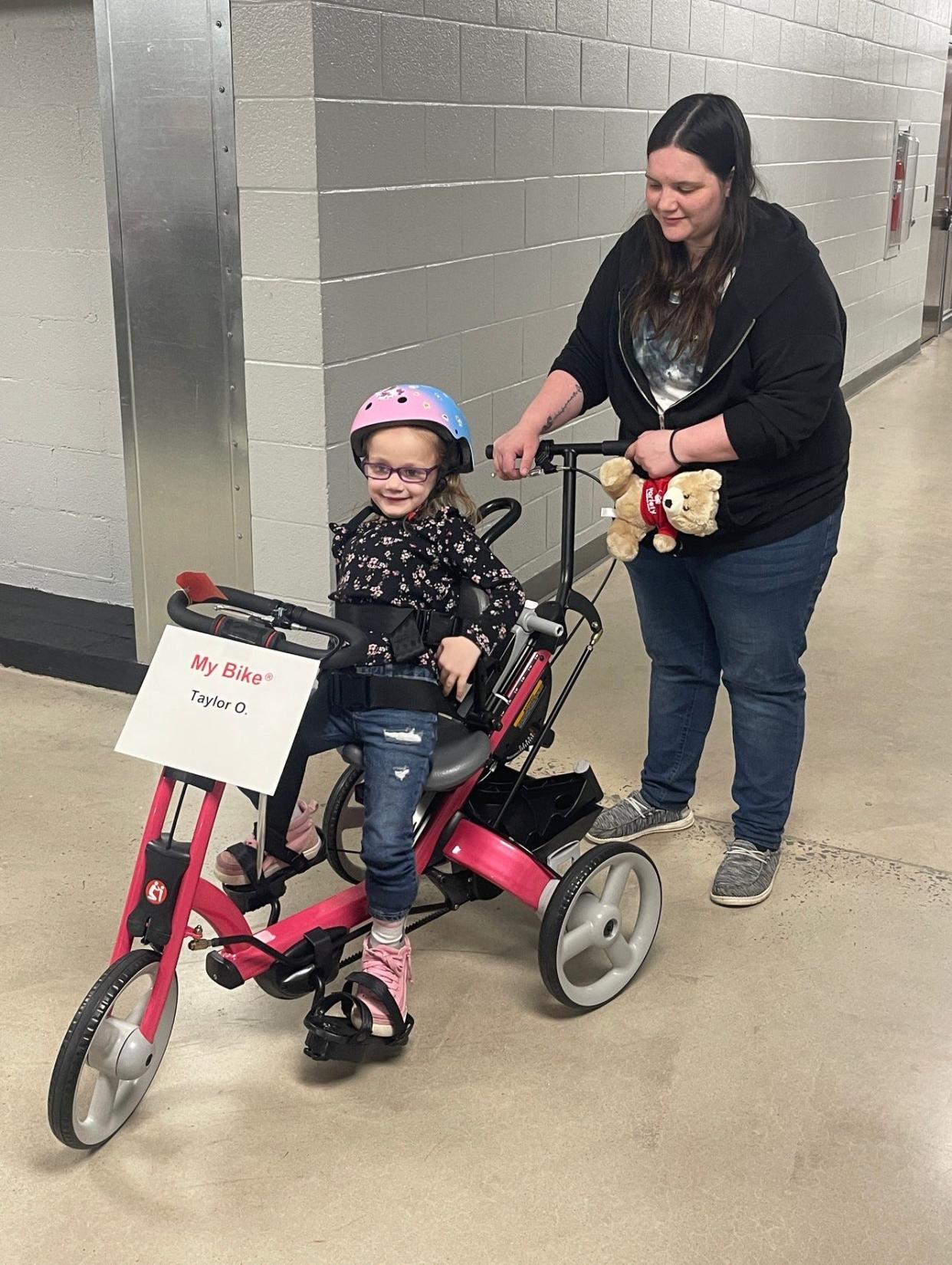 Taylor Ogline sits on her new adaptive bike from Variety, the Children's Charity as her mom, Kaylee Ogline, watches. The Oglines live in Somerset.