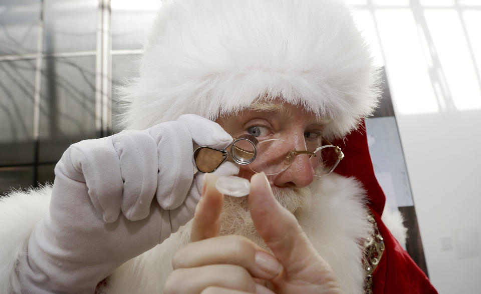 Actor Brady White portrays Santa Claus as he looks at a 25-carat rough Forevermark diamond offered in the Neiman Marcus Christmas Book Tuesday, Oct. 8, 2013, in Dallas. The Forevermark Ulitmate Diamond Experience on sale for $1,850,000 includes a rough diamond and a trip to London and Africa to trace the provenance of the stone. (AP Photo/LM Otero)