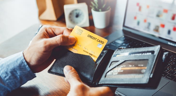 A man pulls a credit card out of his wallet. 