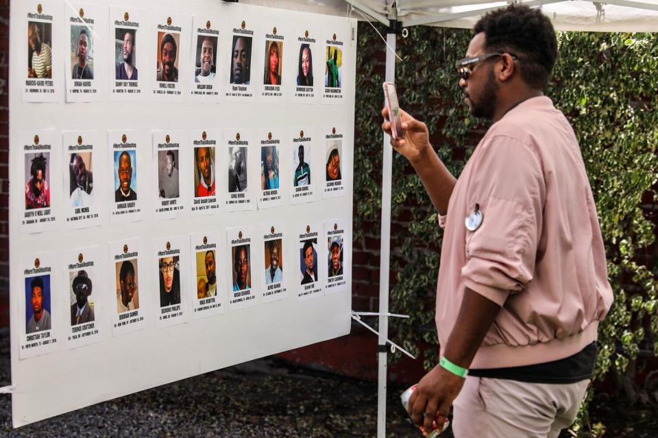 A man in an orange shirt views photos of Black people who have killed by police officers.