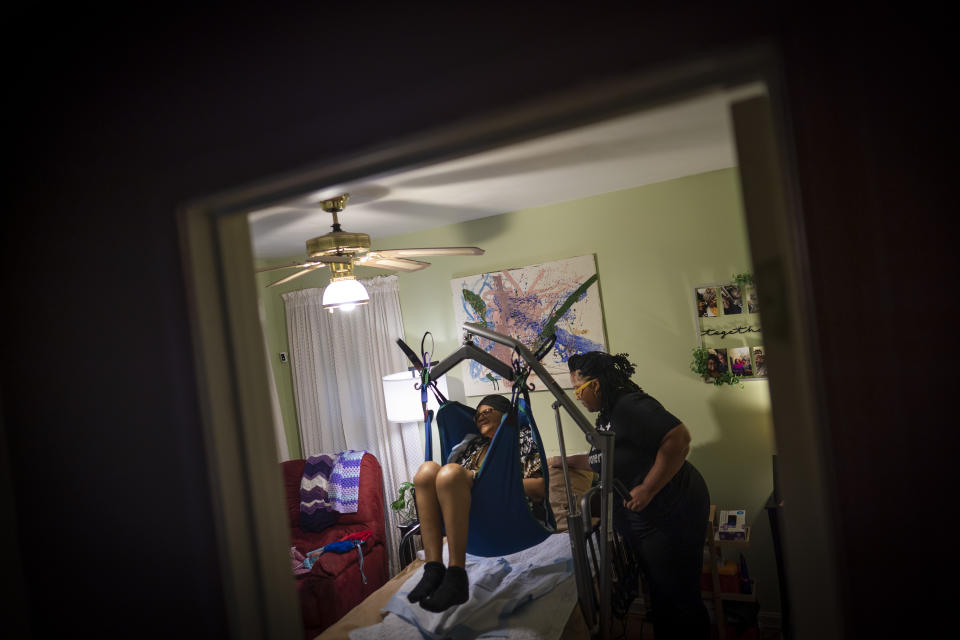 Jessica Guthrie uses a harness to lift her mother, Constance, off her bed and into a wheelchair to go to the living room in Fredericksburg, Va., on Monday, Sept. 19, 2022. Jessica is concerned about how she’ll handle the next medical emergency. She’ll have to rely on local hospitals that provided her mother with problematic care before. “Everything’s gone and it feels like I’m back at square one again,” she says. “I feel like the system’s failed us and has failed so many other caregivers.” (AP Photo/Wong Maye-E)