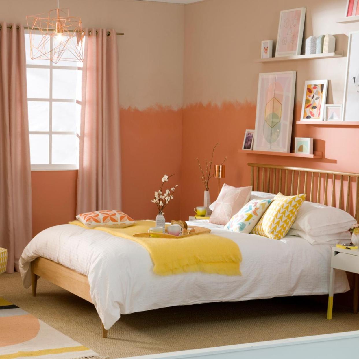  Pale orange bedroom, fitted shelves with framed abstract art, wood double bed position against wall. 