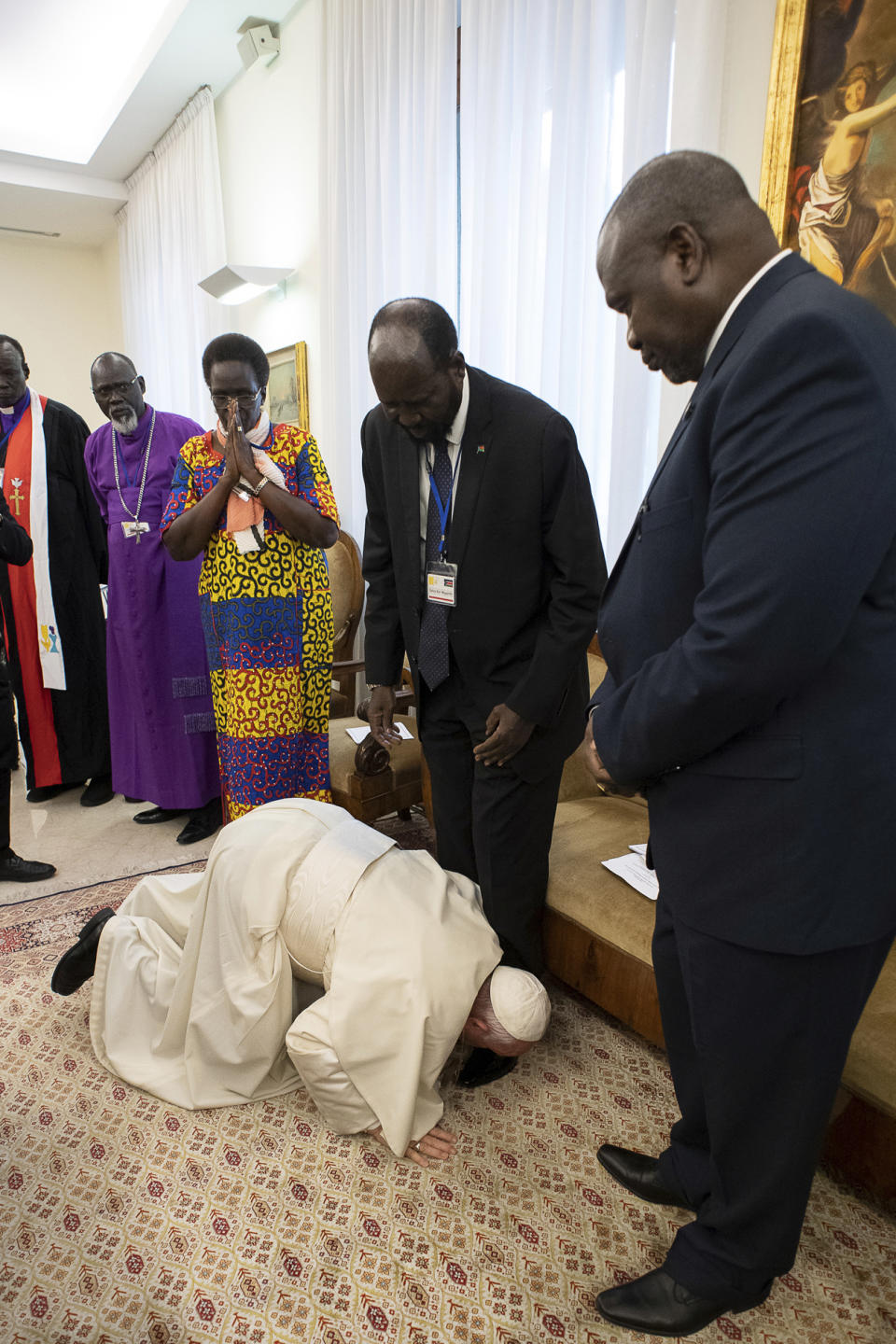 Pope Francis kneels to kiss the feet of South Sudan's President Salva Kiir Mayardit, at the Vatican, Thursday, April 11, 2019. Pope Francis has closed a two-day retreat with South Sudan authorities at the Vatican with an unprecedented act of respect, kneeling down and kissing the feet of the African leaders. (Vatican Media via AP)