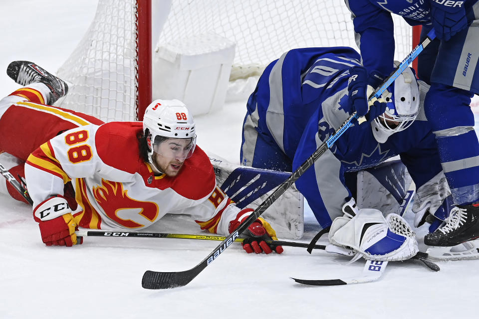 Calgary Flames left wing Andrew Mangiapane (88) tries to knock the puck loose as Toronto Maple Leafs goaltender Michael Hutchinson (30) attempts to cover it during second period NHL hockey action in Toronto on Wednesday, Feb. 24, 2021. (Frank Gunn/The Canadian Press via AP)