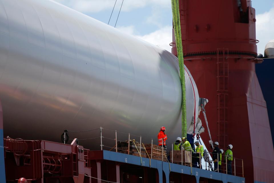 At the Marine Commerce Terminal in New Bedford, longshoremen work on attaching straps to one of three sections of the mast of a wind turbine which arrived Wednesday aboard the first ship carrying turbine components for Vineyard Wind.