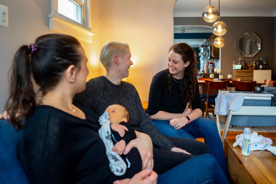 (Left to right) Detroit Doulas co-owner Kirsten Johnson holds 6 week-old Sawyer Basin as she talks with his mothers Alicia Basin and Corinne Rockoff during a post-natal visit to a family at their home in Ferndale on January 13, 2023.