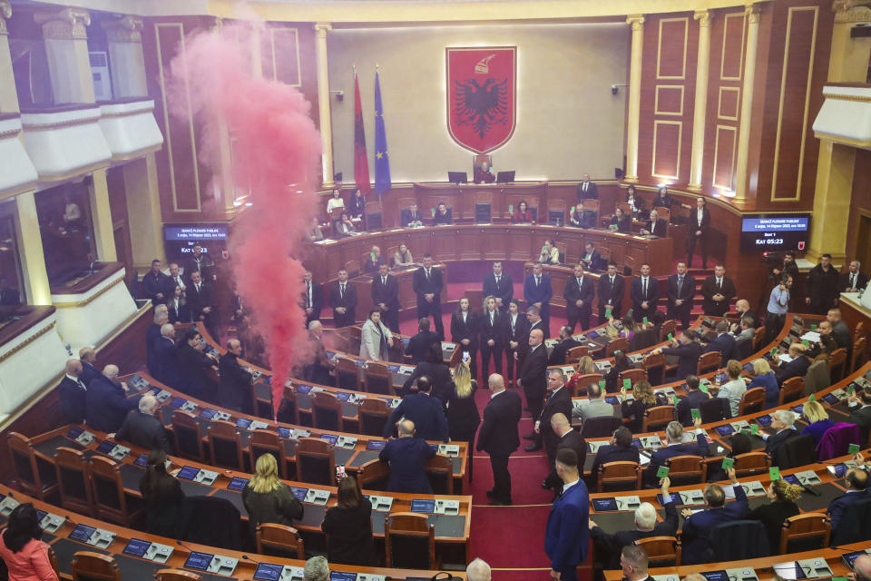 Lawmakers of Democratic Party light a flare inside the Parliament in Tirana, Albania, Thursday, Dec. 14, 2023. Lawmakers in Albania have gathered for a new session that the opposition tried to disrupt demanding the government to be investigated for alleged corruption. (AP Photo/Armando Babani)