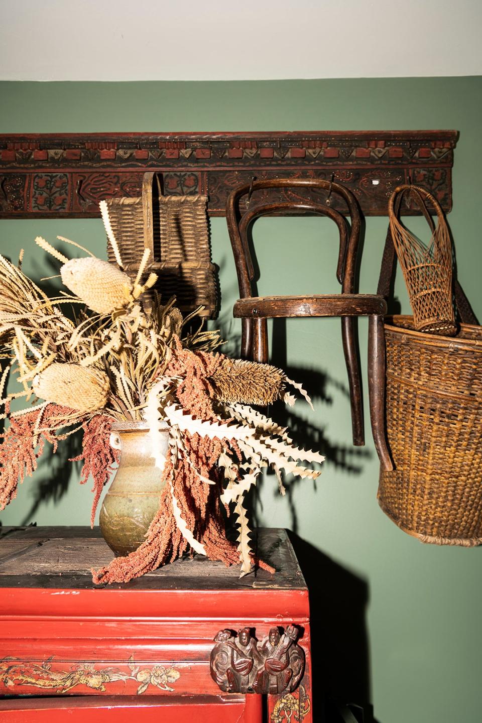 Baskets and chairs hanging in front of a sage wall