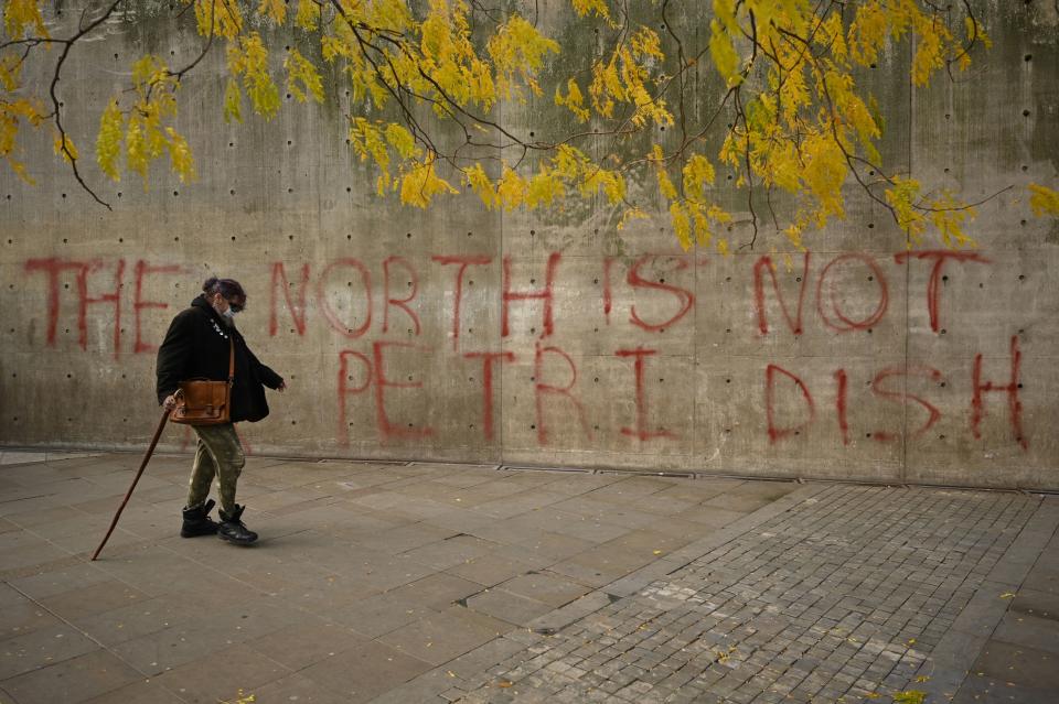 A woman wearing a face-mask walks past graffiti declaring that 'the north is not a petri dish' after Greater Manchester mayor Andy Burnham threatened legal action if Tier 3 restrictions are imposed on the city without agreement, in Picadilly Gardens, central Manchester on October 16, 2020, as the number of cases of the novel coronavirus COVID-19 rises. - The government on Thursday announced more stringent measures but as ministers tightened the screw on social interaction to cut close-contact transmission, they sparked a furious row with leaders in northwest England, where infection rates are highest. Greater Manchester Mayor Andy Burnham accused the government of being "willing to sacrifice jobs and businesses here to try and save them elsewhere". (Photo by Oli SCARFF / AFP) (Photo by OLI SCARFF/AFP via Getty Images)