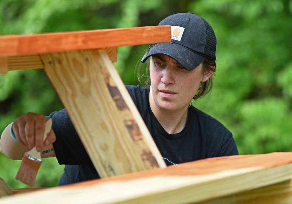 Scarlet South an employee with SafeLite brushes a sealant onto a picnic table at Westerly Hills Academy on Friday, April 19, 2024. South and her co-workers joined employees from other local companies for the 19th Charlotte Playground Build. The playground build is presented by United Way of Greater Charlotte that brings together companies across the community to build a new playground for a local Charlotte-Mecklenburg elementary school.