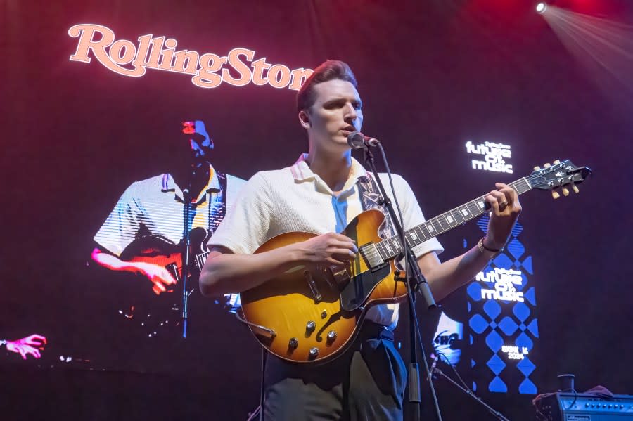 Brandon Coleman, of the Red Clay Strays, performs with a 'Rolling Stones' sign in the background on stage.
