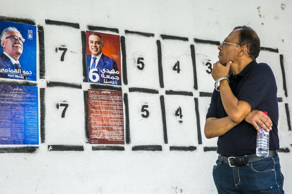 A man looks at a wall of campaign posters in Tunis, Tunisia, Monday, Sept. 2, 2019.Tunisia's 26 presidential candidates have launched their campaigns in a political climate marked by uncertainty, money laundering allegations and worries about violent extremism. (AP Photo/Hassene Dridi)