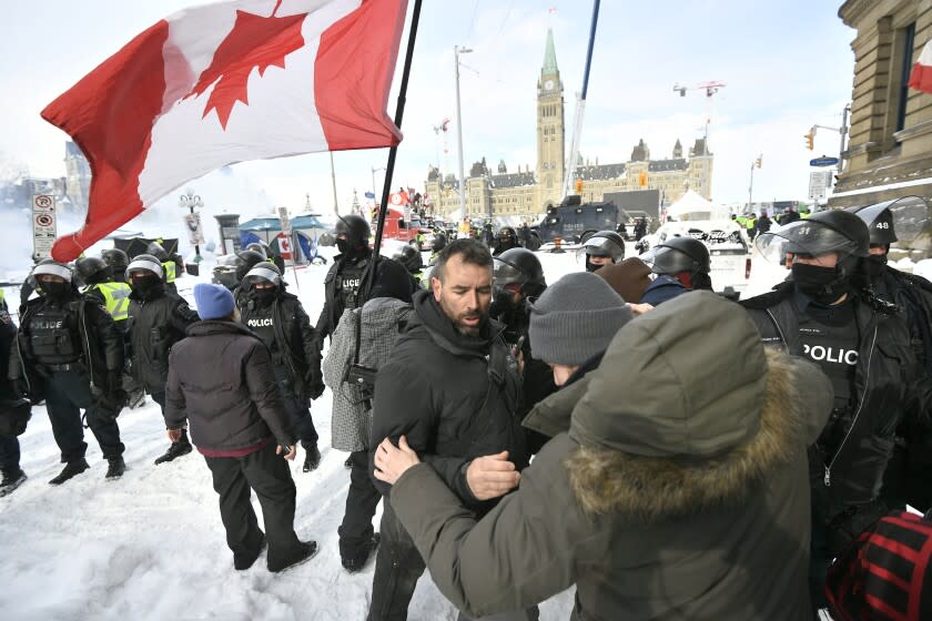 Police move in to clear downtown Ottawa near Parliament Hill on Saturday, Feb. 19, 2022. Police resumed pushing back protesters on Saturday after arresting more than 100 and towing away vehicles in Canada's besieged capital, and scores of trucks left under the pressure, raising authorities' hopes for an end to the three-week protest against the country's COVID-19 restrictions. (Justin Tang /The Canadian Press via AP)