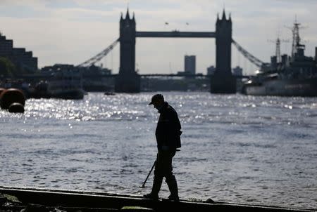 Mudlark Matthew Goode uses a metal detector to look for objects near Tower Bridge on the bank of the River Thames in London, Britain May 23, 2016. REUTERS/Neil Hall