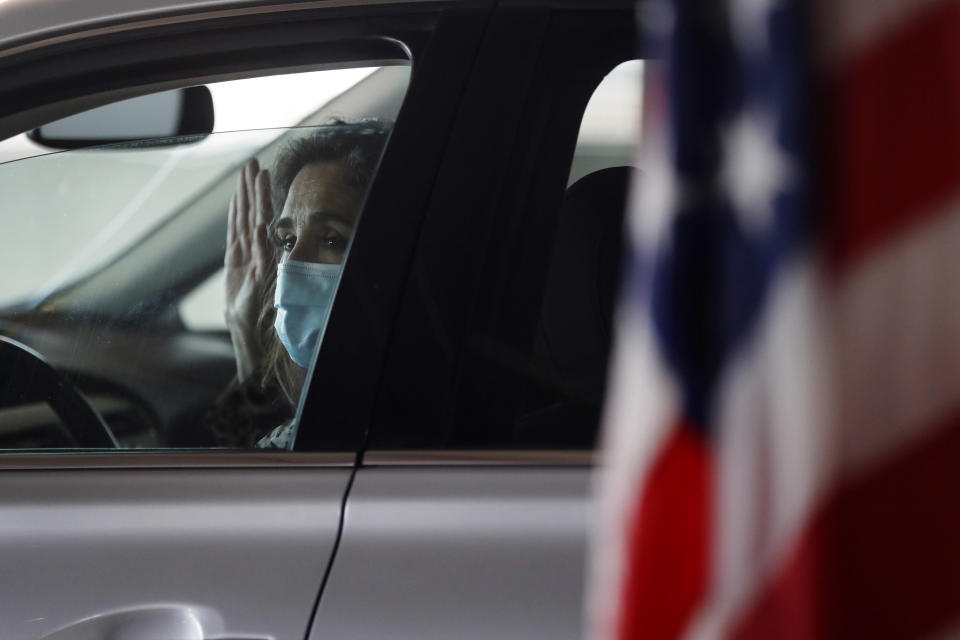 FILE- In this June 26, 2020, file photo, Anita Rosenberger takes the oath of citizenship during a drive-thru naturalization service in a parking structure at the U.S. Citizenship and Immigration Services headquarters on Detroit's east side. U.S. Citizenship and Immigration Services has transformed under President Donald Trump to emphasize fraud detection, enforcement and vetting, which has delayed processing and contributed to severe fiscal problems. Its revamp came as the administration sought to cut legal immigration by making it more dependent on employment skills and wealth tests. (AP Photo/Carlos Osorio, File)