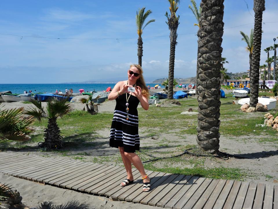 A woman holding a white disc in a tropical place.