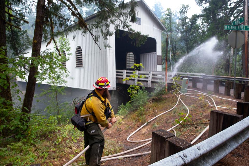 Silverton Fire Lt. Joe Homutoff, part of a crew from the Marion County Fire Task Force tests a sprinkler system set up on the Belknap Covered Bridge in Rainbow in an effort to protect the historic structure from the nearby Lookout Fire bear McKenzie Bridge.