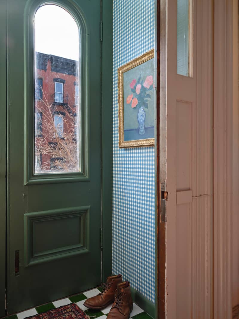 Floral painting mounted in entry way with blue gingham wallpaper in newly renovated home.