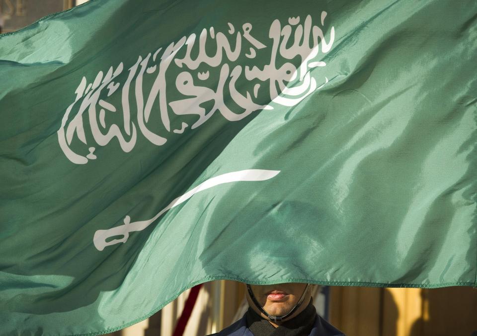 FILE - In this March 22, 2018, file photo, an honor guard member is covered by the flag of Saudi Arabia in Washington. A report released by Amnesty International Wednesday, April 21, 2021, said the number of executions worldwide in 2020 plummeted to its lowest level in at least a decade. But the report said four states in the Middle East — Iran, Egypt, Iraq and Saudi Arabia respectively — topped the global list and pressed on with shootings, beheadings and hangings, ignoring pleas by rights groups to halt executions during the pandemic. (AP Photo/Cliff Owen, File)