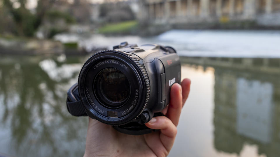 The Canon HF G70 being held in front of a weir