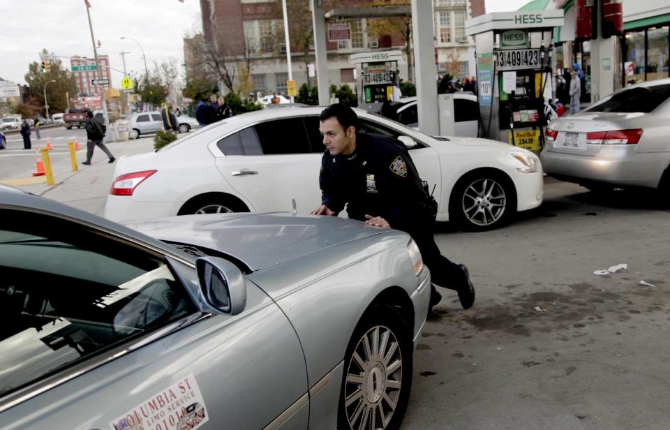 A police officer moves a car that is out of gas, trying to position it so it can fill up, at a gas station in the Brooklyn borough of New York, Friday, Nov. 2, 2012. In parts of New York and New Jersey, drivers face another day of lining up for hours at gas stations struggling to stay supplied. Superstorm Sandy damaged ports that accept fuel tankers and flooded underground equipment that sends fuel through pipelines. Without power, fuel terminals can't pump gasoline onto tanker trucks, and gas stations can't pump fuel into customers' cars. (AP Photo/Seth Wenig)