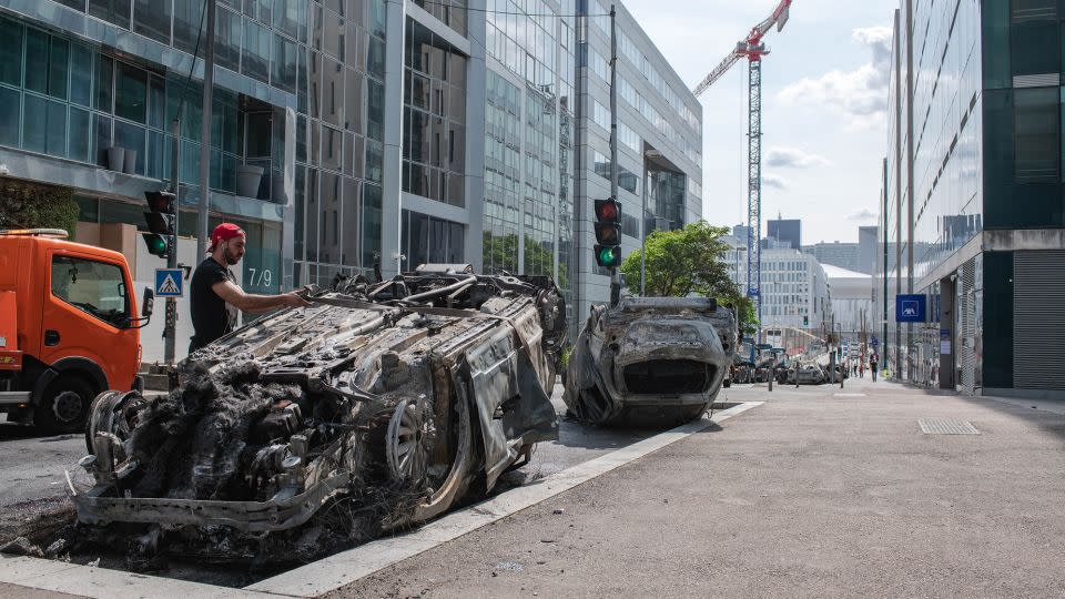 Workers clear a street filled with charred cars in Nanterre, France, on Friday. - Joshua Berlinger/CNN