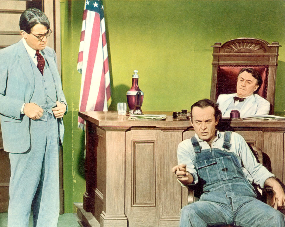 Gregory Peck as Atticus Finch stands near a desk, while James Anderson as Bob Ewell points and Paul Fix as the judge relaxes in a courtroom scene from To Kill a Mockingbird