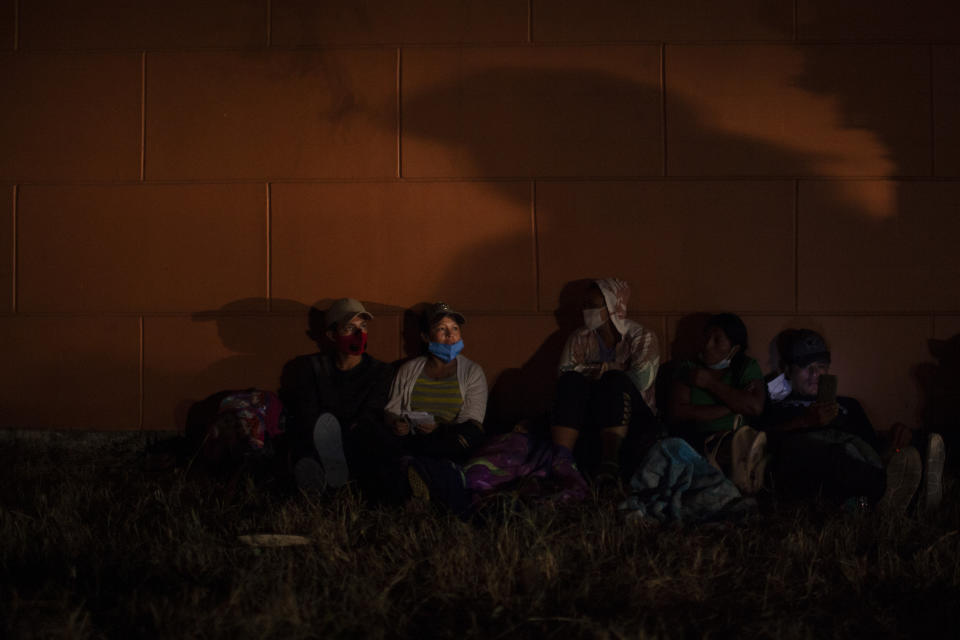 Honduran migrants hoping to reach the U.S. border rest on the side of a highway, as soldiers patrol the road in Vado Hondo, Guatemala, Saturday, Jan. 16, 2021. Guatemalan authorities estimated that as many as 9,000 Honduran migrants crossed into Guatemala as part of an effort to form a new caravan to reach the U.S. border. (AP Photo/Sandra Sebastian)