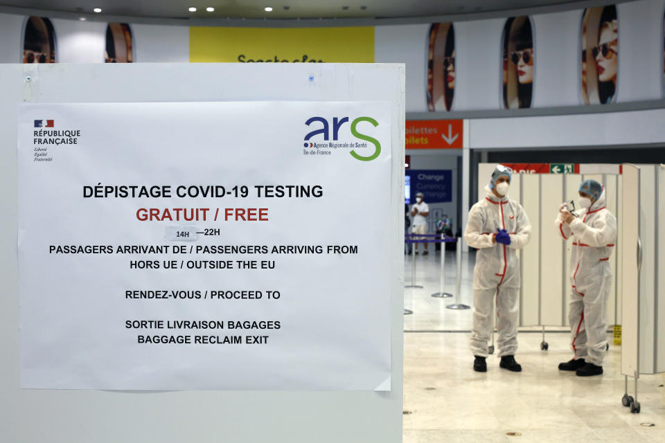 Health workers wait to test passengers with the COVID-19 test, at the Roissy Charles de Gaulle airport, outside Paris, Saturday, Aug. 1, 2020. Travelers entering France from 16 countries where the coronavirus is circulating widely are having to undergo virus tests upon arrival at French airports and ports.(AP Photo/Thibault Camus)